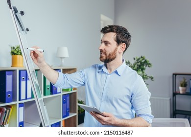 Young businessman writing on white board with marker business strategy plan, man working in modern bright office