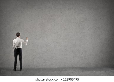 Young Businessman Writing Something On A Large Empty Wall