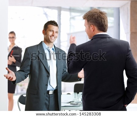 Young businessmen talking at meetingroom, smiling happy.