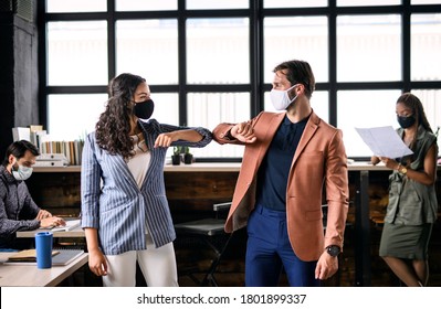 Young Businesspeople With Face Masks Working Indoors In Office, Greeting.