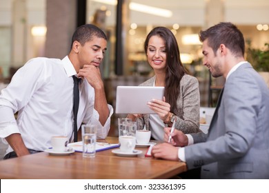 Young businesspeople having a business meeting at coffee table - Powered by Shutterstock