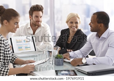 Young businesspeople sitting in meetingroom, having meeting, chatting in good mood.