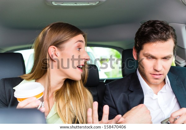 Young businesspeople\
traveling in taxi, and talking about some things perhaps they are\
colleagues