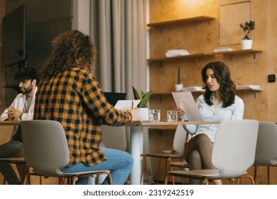 Young businesspeople working together at the cafe of modern co working space. They are reading a document - Shutterstock ID 2319242519