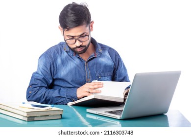 Young Businessperson Reading Something On Diary In Front Of A Laptop