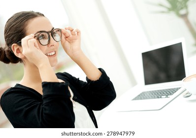 Young Businesswoman Adjusting Her Glasses As She Prepares To Start Working On Her Laptop Computer On Her Desk