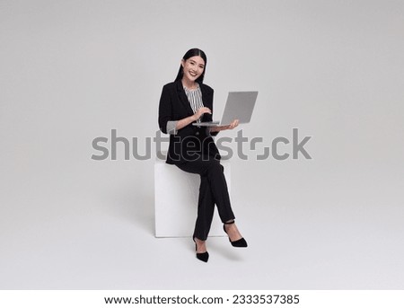 Young businesswoman asian happy smiling. While her using laptop sitting on white chair isolated on copy space white studio background.