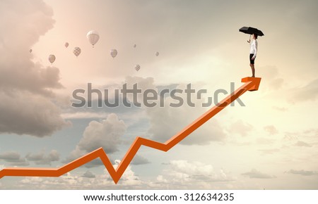 Young businesswoman with black umbrella standing on graph top