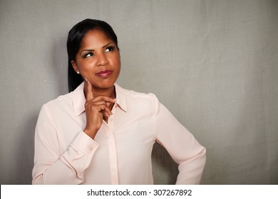 Young Businesswoman In Button Down Shirt Planning With Hand On Chin - Copy Space