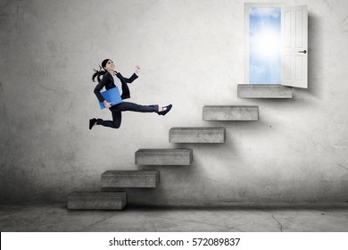 Young businesswoman carrying a document and climbs a staircase toward an opportunity door to success