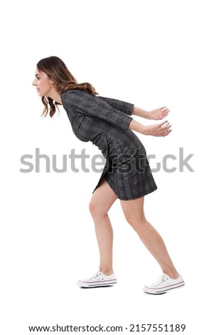 Young businesswoman carrying an imaginary burden or heavy weight on her back, isolated on white background