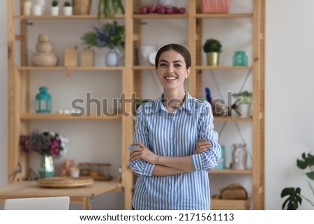 Young businesswoman in casual elegant blouse posing in office with arms crossed smile look at camera feel satisfied by career in company. Independent woman portrait, teacher pose at workplace concept