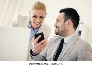 Young businesswoman communicating with businessman and smiling.They are working at meeting in office.