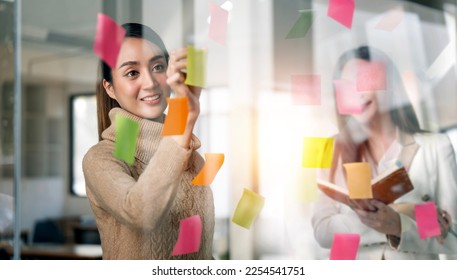 Young  businesswoman creative team using post it notes in glass wall to writing strategy business plan to development grow to success. - Shutterstock ID 2254541751
