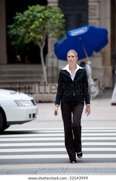 A young businesswoman crossing the road at a\
zebra crossing