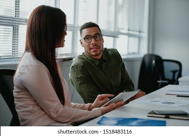 Young businesswoman discussing something positive using digital tablet with her male colleague at workplace - Shutterstock ID 1518483116