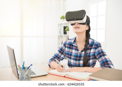 young businesswoman drawing design with VR headset glasses device writing with pen on the notebook and happy looking at 3d video film in the virtual reality tech. - Powered by Shutterstock