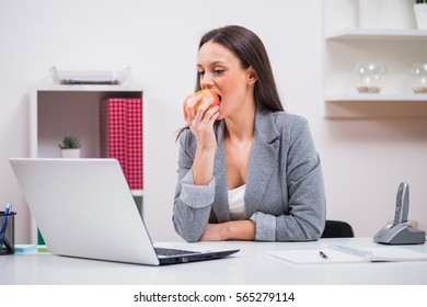 Young Businesswoman Is Eating Apple In Her Office.