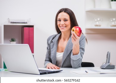 Young Businesswoman Is Eating Apple In Her Office.