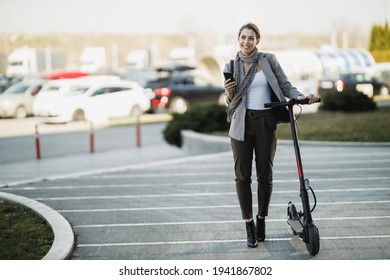 Una joven empresaria con una motocicleta eléctrica yendo a trabajar y usando un smartphone.