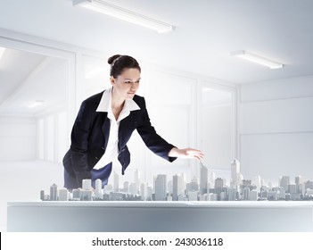 Young businesswoman examining model of construction project - Powered by Shutterstock