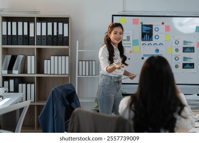 Young businesswoman explaining project strategy to colleagues during a meeting in a modern office, promoting teamwork and collaboration in achieving business success - Powered by Shutterstock