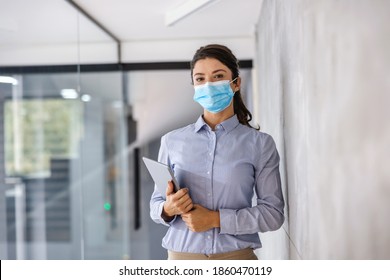 Young businesswoman with face mask standing in corporate firm with tablet in hands during corona virus. - Powered by Shutterstock