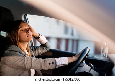 Young Businesswoman Feeling Bored While Driving A Car And Being Stuck In Traffic Jam. 