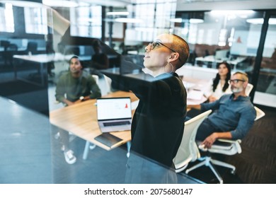 Young businesswoman giving a presentation to her colleagues. Creative young businesswoman presenting significant data in a boardroom. Group of modern businesspeople attending a briefing.