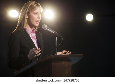 Young Businesswoman Giving Speech At Podium In Auditorium