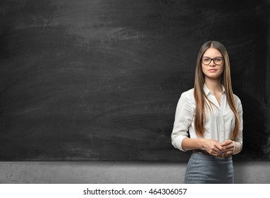 Young businesswoman with glasses standing in front of blank blackboard. Business staff. School and education. Office clothes. Learning and teaching. - Powered by Shutterstock