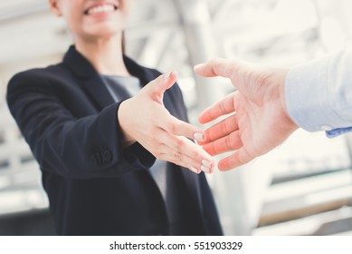 Young businesswoman going to make handshake with a businessman -greeting, dealing, merger and acquisition concepts