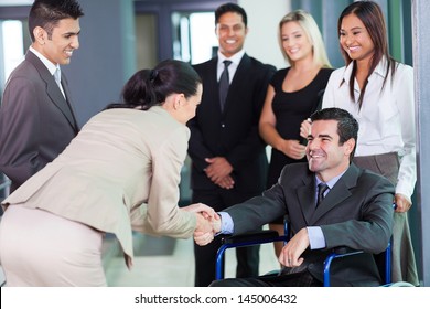 young businesswoman greeting handicapped business partner and team - Powered by Shutterstock