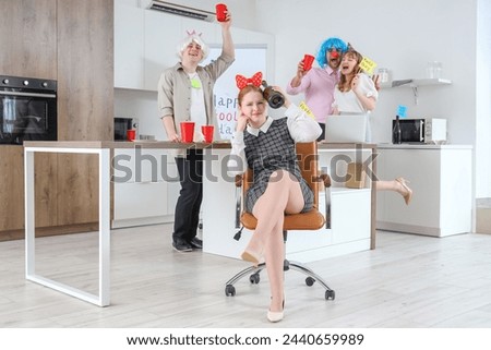 Young businesswoman with her colleagues celebrating April Fools' Day in kitchen at office party