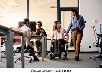 Young businesswoman and her female coworker in wheelchair planning while working at corporate office.  - Powered by Shutterstock