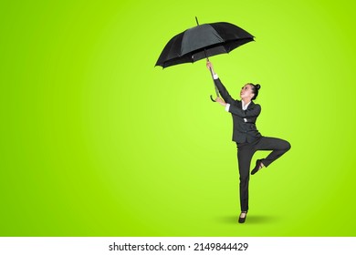 Young businesswoman holding an umbrella while dancing with ballet movement in the studio with green screen background - Powered by Shutterstock