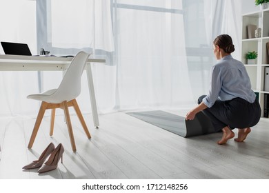 Young Businesswoman Laying Fitness Mat On Floor In Office