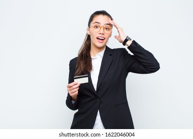 young businesswoman looking happy, astonished and surprised, smiling and realizing amazing and incredible good news with banknotes with bills