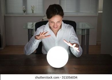 Young Businesswoman Looking Into The Future In A Crystal Ball In Office