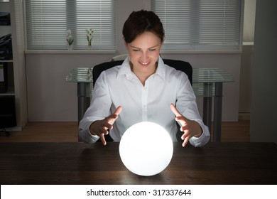 Young Businesswoman Looking Into The Future In A Crystal Ball In Office