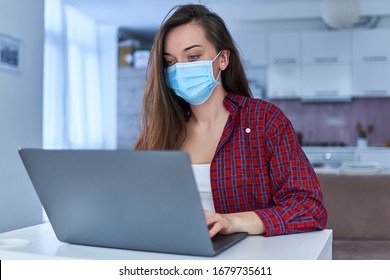 Young businesswoman in a medical protective mask works from home at the computer during self-isolation and quarantine. Virus coronavirus outbreak, flu epidemic and covid ncov novel. Stay home - Powered by Shutterstock