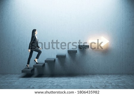 Young businesswoman moving up on stairs with arrow on gray wall. Leadership and career development concept.