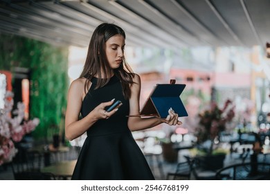 A young businesswoman multitasks with a smart phone and tablet while in an outdoor cafe. She is focused and productive. - Powered by Shutterstock