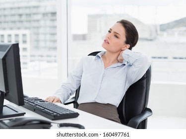 Young Businesswoman With Neck Pain Sitting At Office Desk