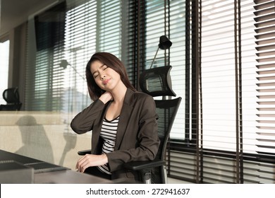 Young Businesswoman With Neck Pain Sitting At Office Desk