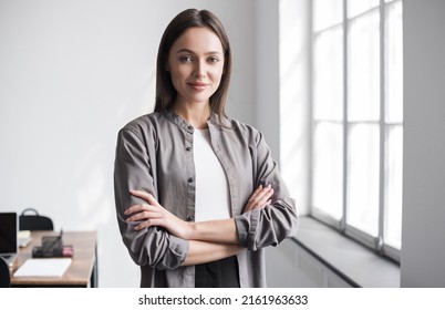 Young Businesswoman In Office Portrait. Self Confident Young Woman With Crossed Arms In Office. People, Candid Portraits, Business, Lifestyle Concept