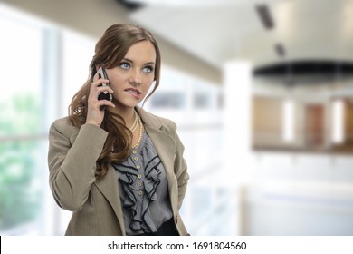 Young businesswoman on the cell phone inside her office building making faces