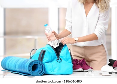 Young Businesswoman Packing Sports Stuff For Training Into Bag In Office