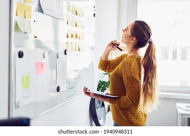 Young businesswoman planning in office using whiteboard and digital tablet