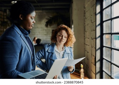 Young businesswoman reading document with colleague in office - Powered by Shutterstock